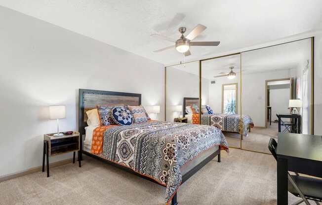 A bedroom with a bed, a chair, and a mirror.