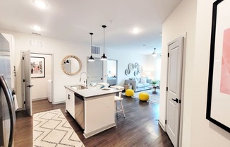 a kitchen and living room with white walls and hardwood floors