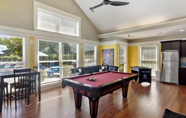 a pool table in a living room with windows