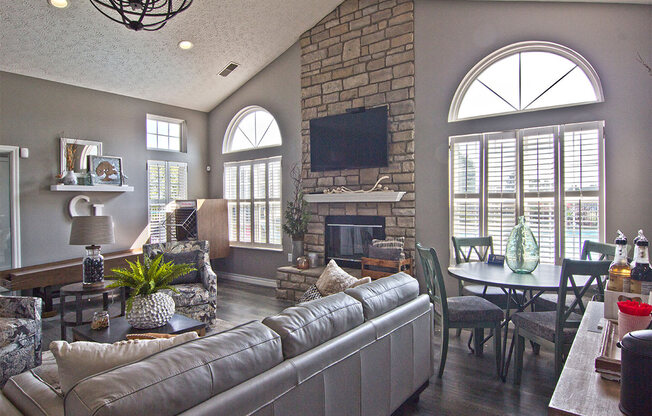 A living room with a grey couch and a stone fireplace.