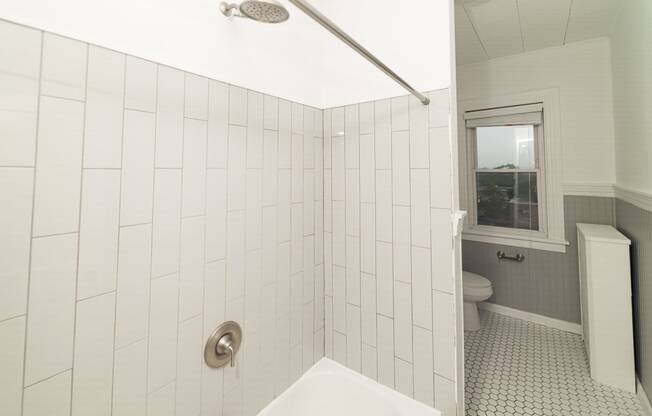 a white tiled bathroom with a tub and a toilet at The Packard, Connecticut