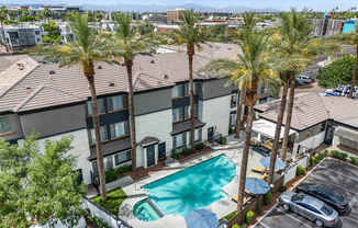 A swimming pool surrounded by palm trees and apartment buildings.
