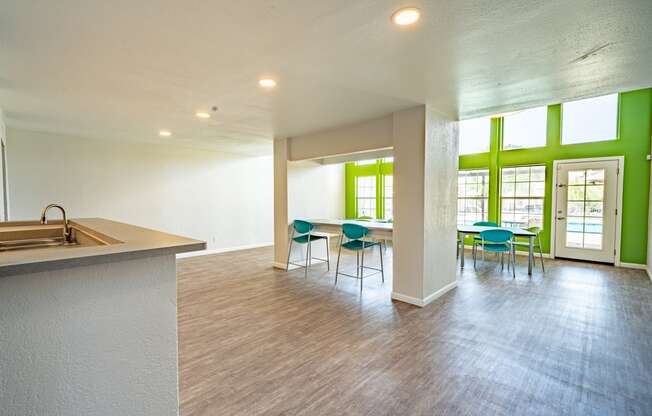 an open living room with a kitchen and dining area with green walls and windows
