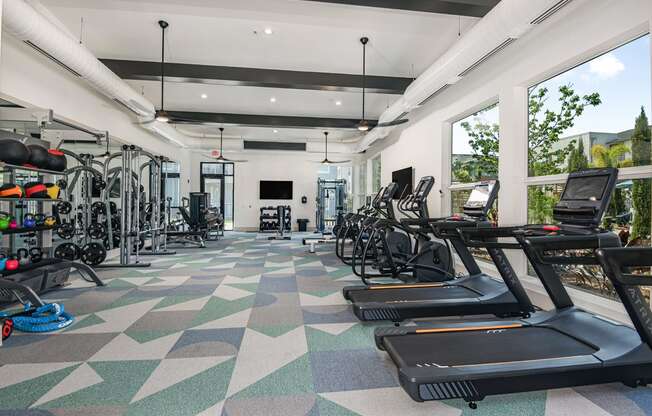 a workout room with treadmills and other exercise equipment