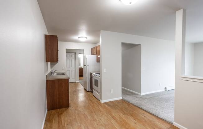 a living room and kitchen with wood floors and white walls