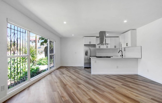 an open living room with a kitchen and a large window