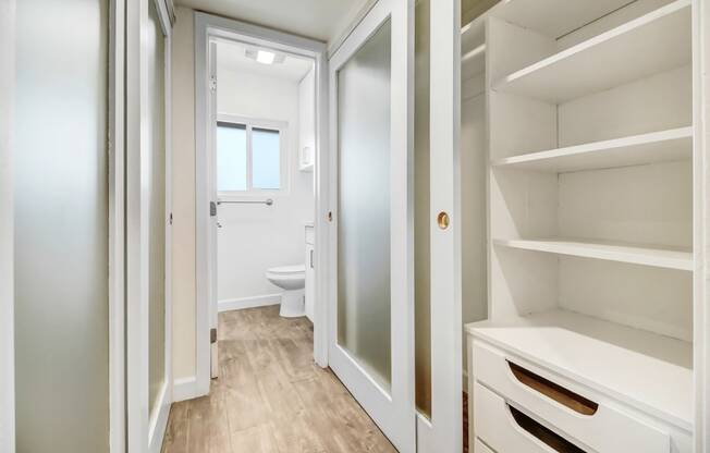 a walk in closet with a door to a bathroom with a toilet