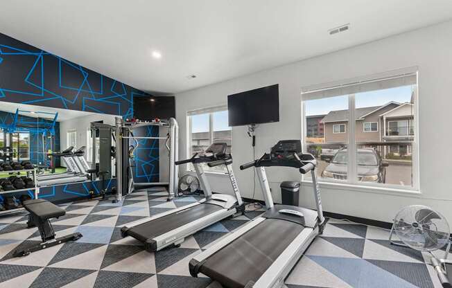 A treadmill and a bench are in a gym with a window showing a residential area.