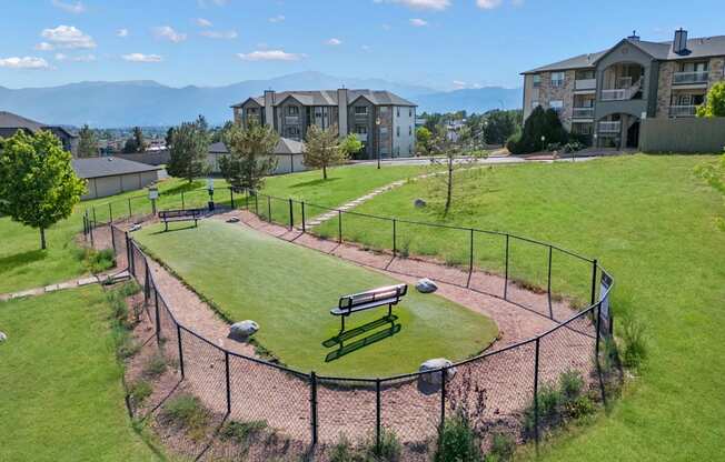a park with a fenced in field and houses in the background