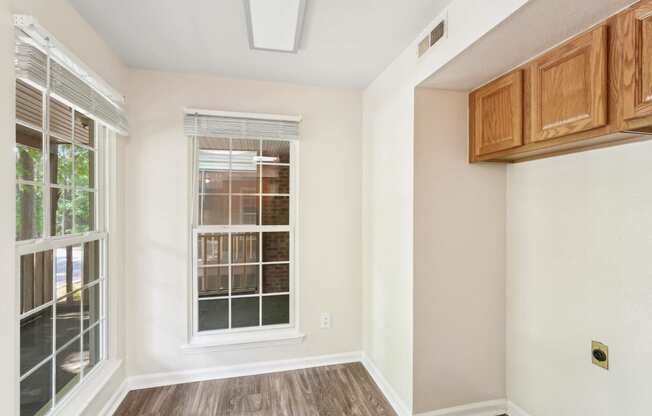 an empty room with a window and wooden floors and cabinets