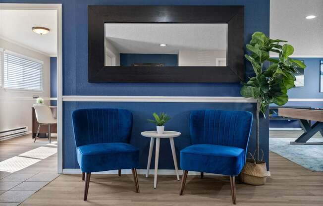Two blue chairs are placed in front of a mirror.