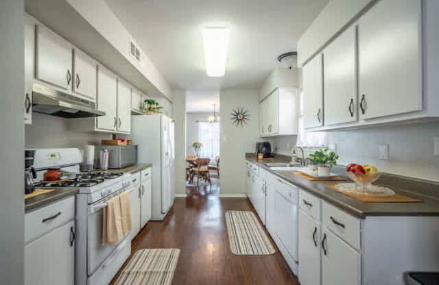 A kitchen with white cabinets and a wooden floor.