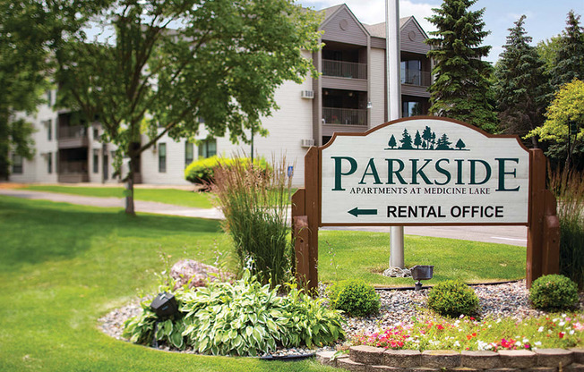 Sign that says "Parkside apartments at Medicine Lake" on it with the words "Rental Office" and a left arrow below it