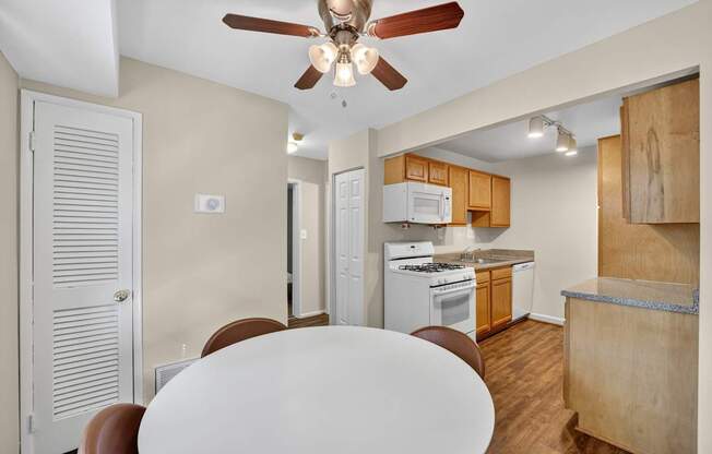 A kitchen with a white ceiling fan and a white table.