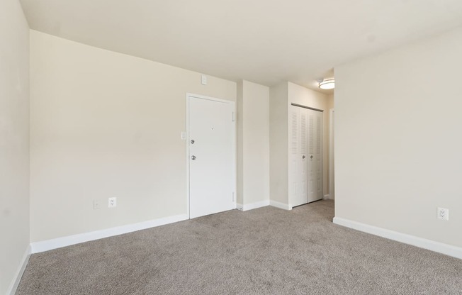 A room with carpeted floor and two white doors.