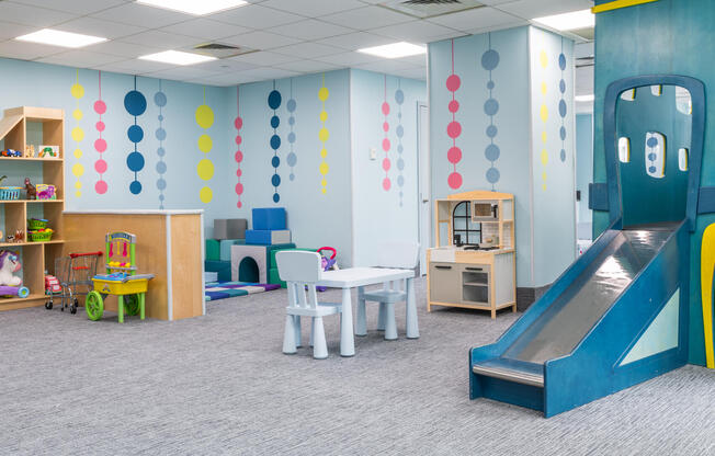 Bright and colorful children's playroom amenity space with slides and toys for residents with childr