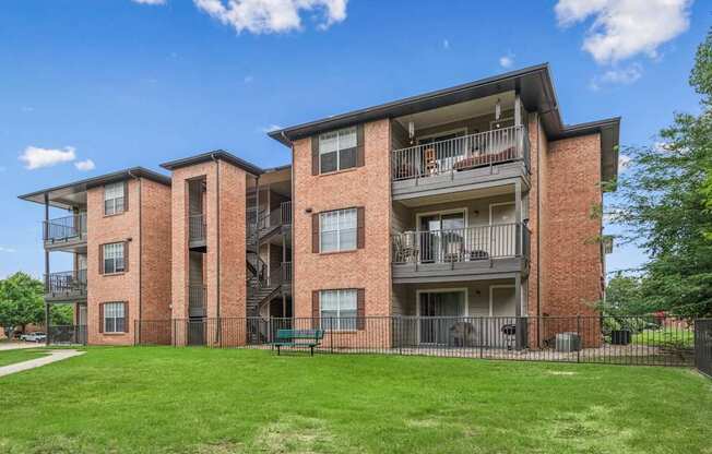 A large brick apartment building with a green lawn in front.