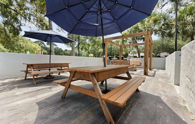 a picnic table with umbrellas and benches on a patio