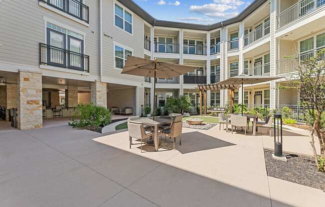A sunny day at a courtyard with a table and chairs and umbrella.