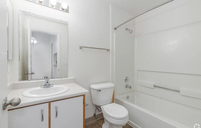 A white bathroom with a sink, toilet and bathtub.