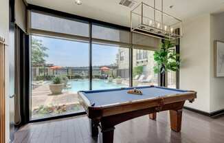 a pool table in a room with a view of a swimming pool