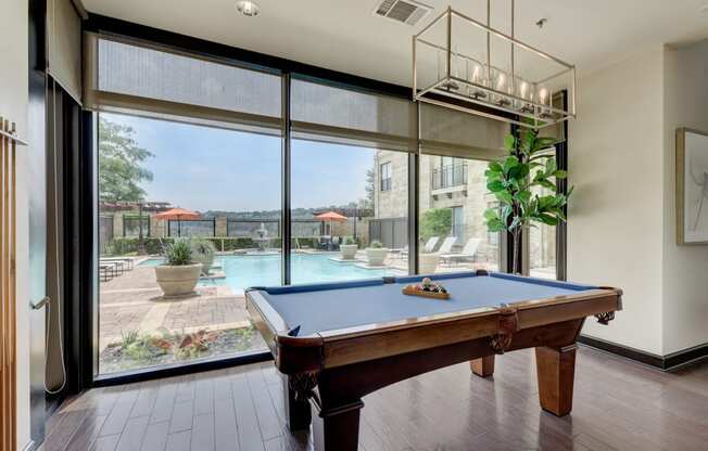a pool table in a room with a view of a swimming pool