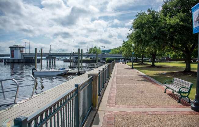 a walkway next to the water with boats and benches