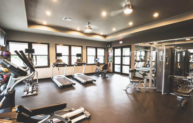 a gym with various exercise equipment and windows