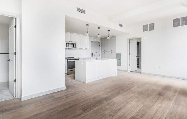 an empty living room and kitchen with white walls and wood floors at The Commonwealth Building, Pittsburgh, Pennsylvania