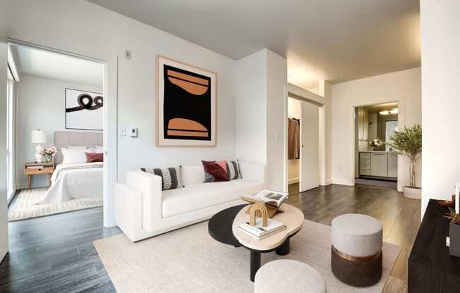 A living room with a white couch and a painting on the wall.