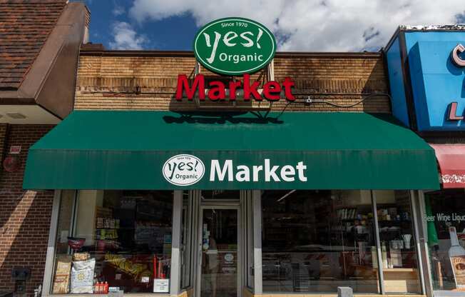 the front of a yes market store with a green awning