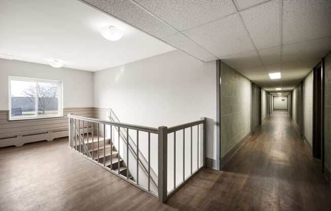 the upstairs hallway of a building with stairs and a window