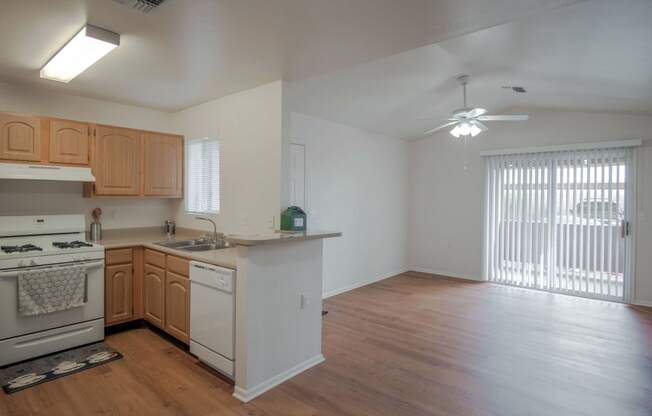 an empty kitchen and living room with wood flooring and a window