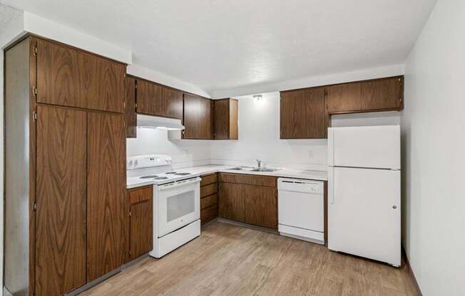 A kitchen with white appliances and wooden cabinets.