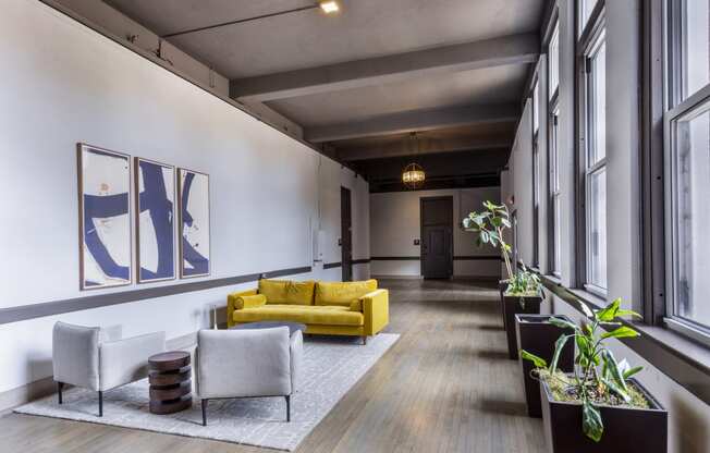 a living room with a yellow couch and chairs and large windows