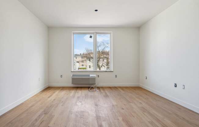 an empty room with wooden floors and a large window