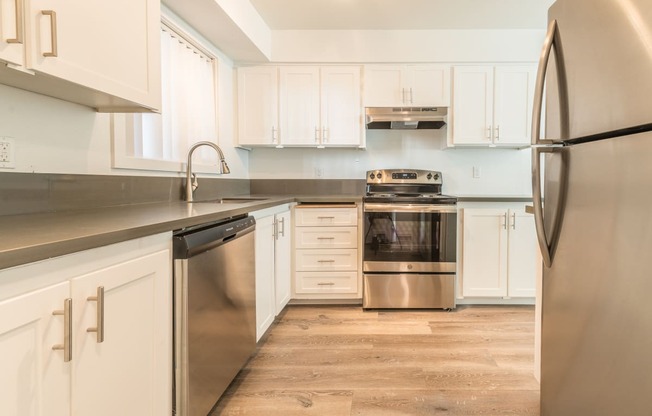 a kitchen with white cabinets and stainless steel appliances