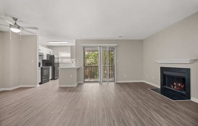 an empty living room with a fireplace and a kitchen