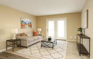 A living room with a grey couch, a coffee table, and a painting on the wall.