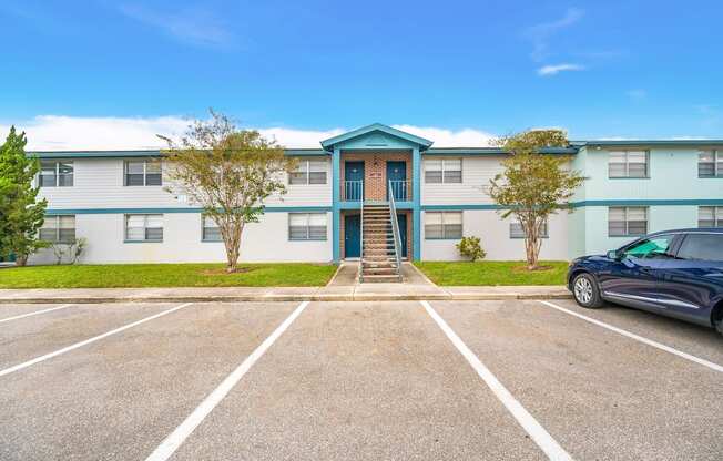 an empty parking lot in front of an apartment building with a car