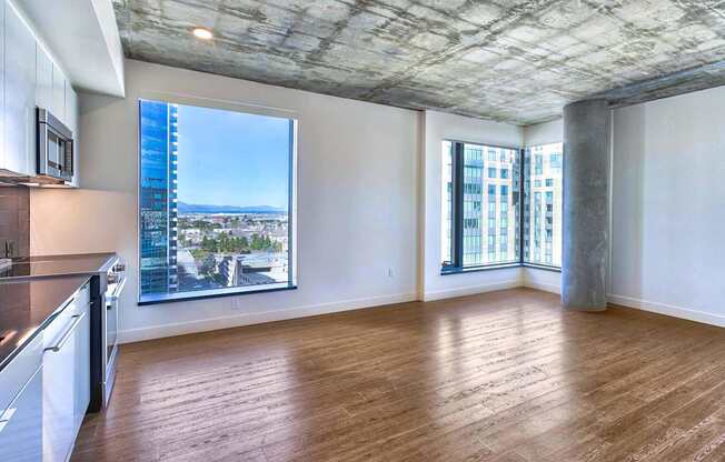 A spacious room with wooden floors and a large window overlooking a cityscape.