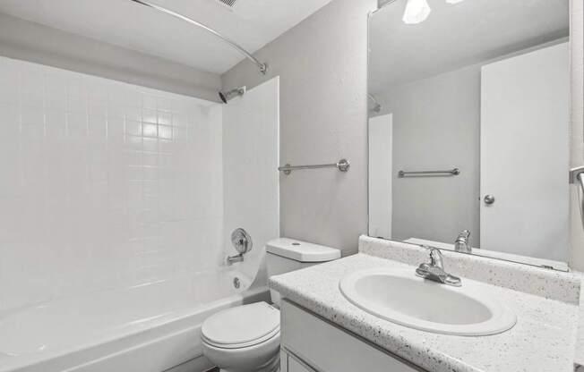 A white bathroom with a toilet, sink, and bathtub.