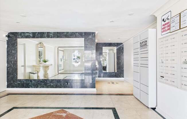 A white reception desk with a sign that says "BURTON SQUARE" is in the middle of a room with a marble floor.