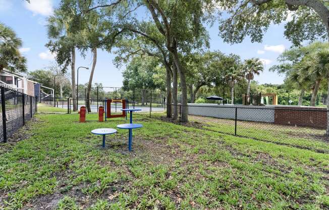 a playground and picnic table in a park with a tennis court