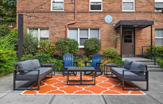 A patio with a table and chairs in front of a brick building.