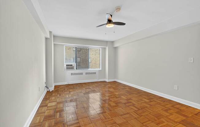A room with a ceiling fan and a window with blinds.