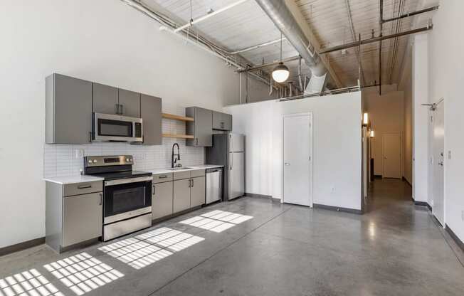 a kitchen with stainless steel appliances and white walls at Highland Mill Lofts, Charlotte