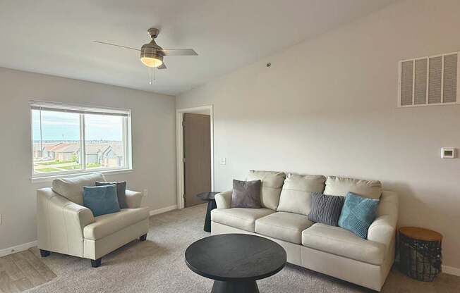 A living room with a white couch, a black coffee table, and a ceiling fan.