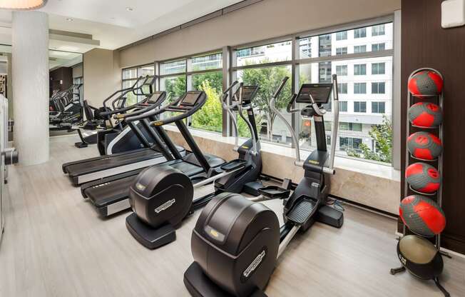 a gym with treadmills and other exercise equipment in a building with large windows