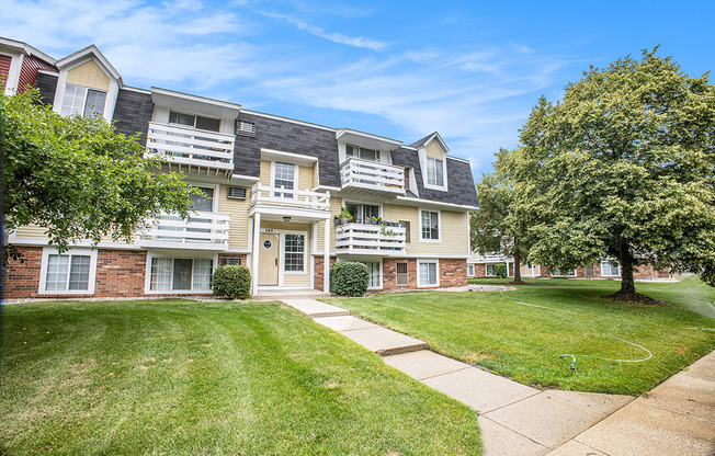 A large grassy area in front of an apartment building with trees at Apple Ridge Apartments, Michigan, 49534